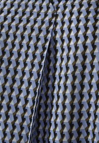 Tyget har ett blårutigt mönster med svarta och olivgröna inslag, med en synlig söm och mjuka veck.