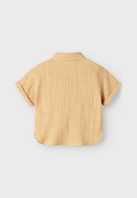 Lühikeste varrukatega, kraega helesinine särk tekstuuriga kangast. Omab ümarat helge ja peent ristpateri mustrit.