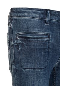 Jeans in denim blu scuro con un taglio classico dritto. Presentano una tasca posteriore con dettagli di cucitura. Texture liscia e finitura leggermente sbiadita.