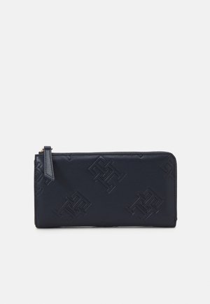Portafoglio in pelle blu navy con motivi geometrici in rilievo, texture liscia, chiusura con zip e un sottile logo sul lato.