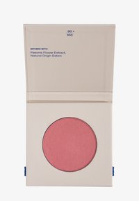 Estuche de maquillaje compacto beige con una pastilla de sonrosador rosa, etiquetada como "90+100", infusionada con extracto de flor de Peonía y ésteres de origen natural.