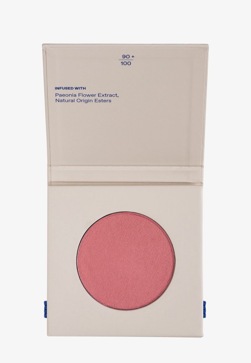 Estuche de maquillaje compacto beige con una pastilla de sonrosador rosa, etiquetada como "90+100", infusionada con extracto de flor de Peonía y ésteres de origen natural.