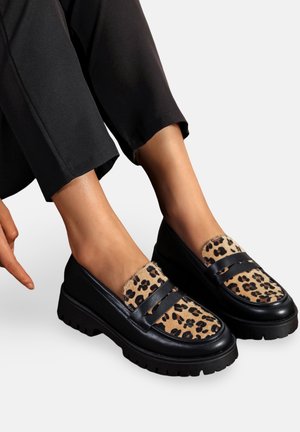 Bottines noires avec un dessus en imprimé léopard fait d'un matériau texturé, présentant deux rayures noires et une semelle épaisse et nervurée.
