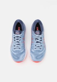 Une paire de chaussures de course Asics Gel Nimbus bleu et corail vue de dessus sur un fond blanc.
