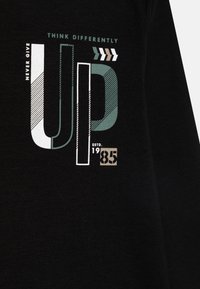 Fekete szövet fehér, türkiz és szürke grafikus szöveggel. A design mintákat tartalmaz, és a "NE ADD FEL" feliratot, amely alatt az "ESTD. 1985." áll.