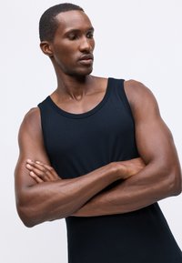 Μαύρο αμάνικο μπλουζάκι φτιαγμένο από απαλό ύφασμα, με στρογγυλή λαιμόκοψη και εφαρμοστό σχέδιο που αναδεικνύει τους μυώδης βραχίονες.