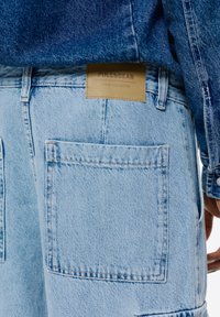 Svetlo modri jeans kratke hlače z dvema velikima zadnjima žepoma. Imajo pečat v svetlo rjavi barvi z napisom "PULL&BEAR DENIM COLLECTION" našit na pasu.