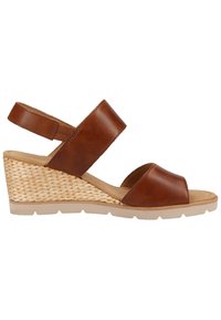 Sandale compensée en cuir marron avec talon tressé, larges brides sur les orteils et la cheville, et semelle en caoutchouc beige.