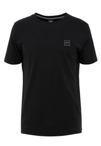 Camiseta de algodón negra con cuello redondo, mangas cortas y un parche de logo cuadrado en el lado izquierdo del pecho. Textura suave, diseño minimalista.