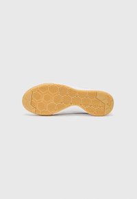 Weißer Sneaker mit einer Gummisohle und hexagonalem Profil. Schlichtes Design, runde Zehenpartie und minimale Akzente.
