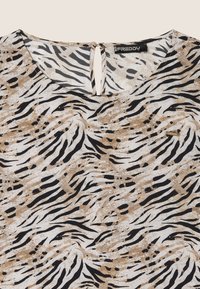 Top a rayas marrón y negro con una textura suave, con escote redondo y un detalle de ojal en la parte posterior. Acento del logo de Freddy cerca del dobladillo.