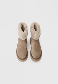 Bottines en suède beige avec un revers en fausse fourrure, bout rond et semelle en caoutchouc avec un bord motif. La vue du dessus révèle la texture douce du revers.