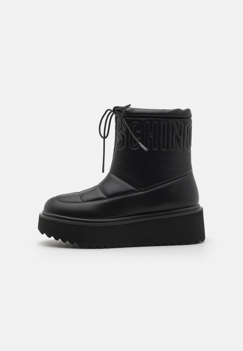 Μαύρες πλατφόρμες μποτάκια αστραγάλου με επενδυμένο σχέδιο, που διαθέτουν στρογγυλή μύτη και ανάγλυφο λογότυπο. Φτιαγμένα από λείο δέρμα με υφή στη σόλα.