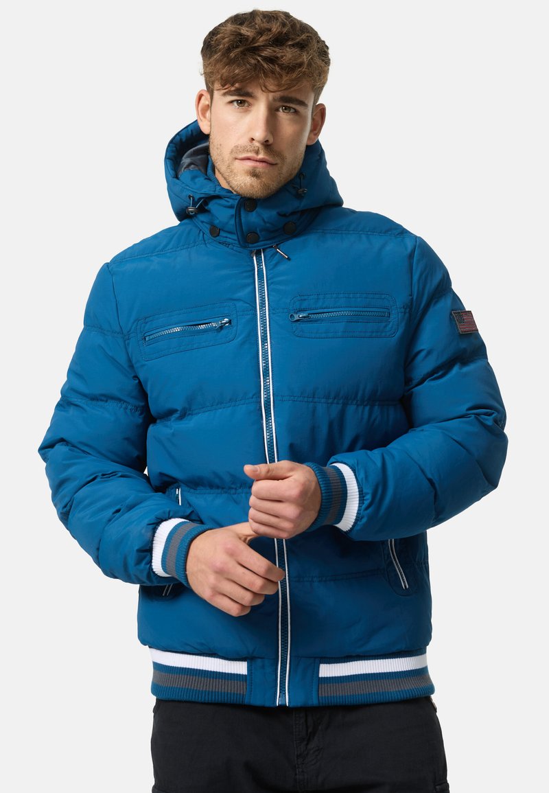 Blue insulated puffer jacket with a hood, contrasting white and blue-striped ribbed hem and cuffs, and two zippered chest pockets.