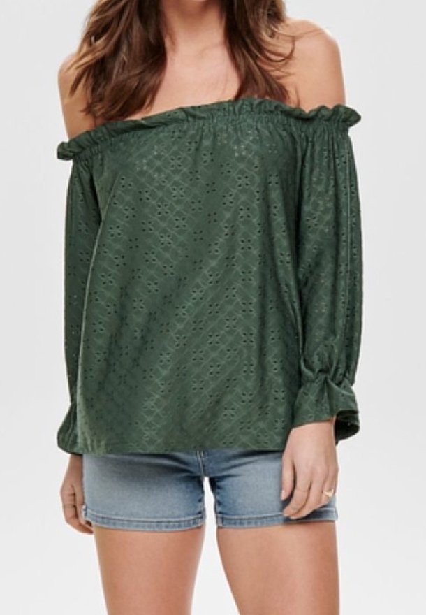 Off-the-shoulder, dark green blouse with textured pattern, ruffled edges, and long sleeves tied at wrists, paired with denim shorts.