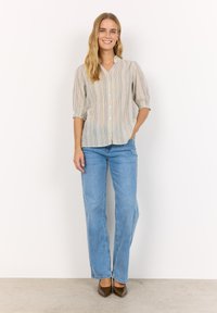 Chemise rayée à manches longues en tissu léger, dotée d'un col et de manches bouffantes. Associée à un jean droit bleu clair et à des talons marron.