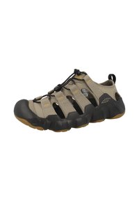 Beige Outdoorschuhe mit einem atmungsaktiven Mesh-Obermaterial, elastischem Schnürsystem, Gummizehenschutz und strukturiertem schwarzen Sohle mit einem Profilmuster.