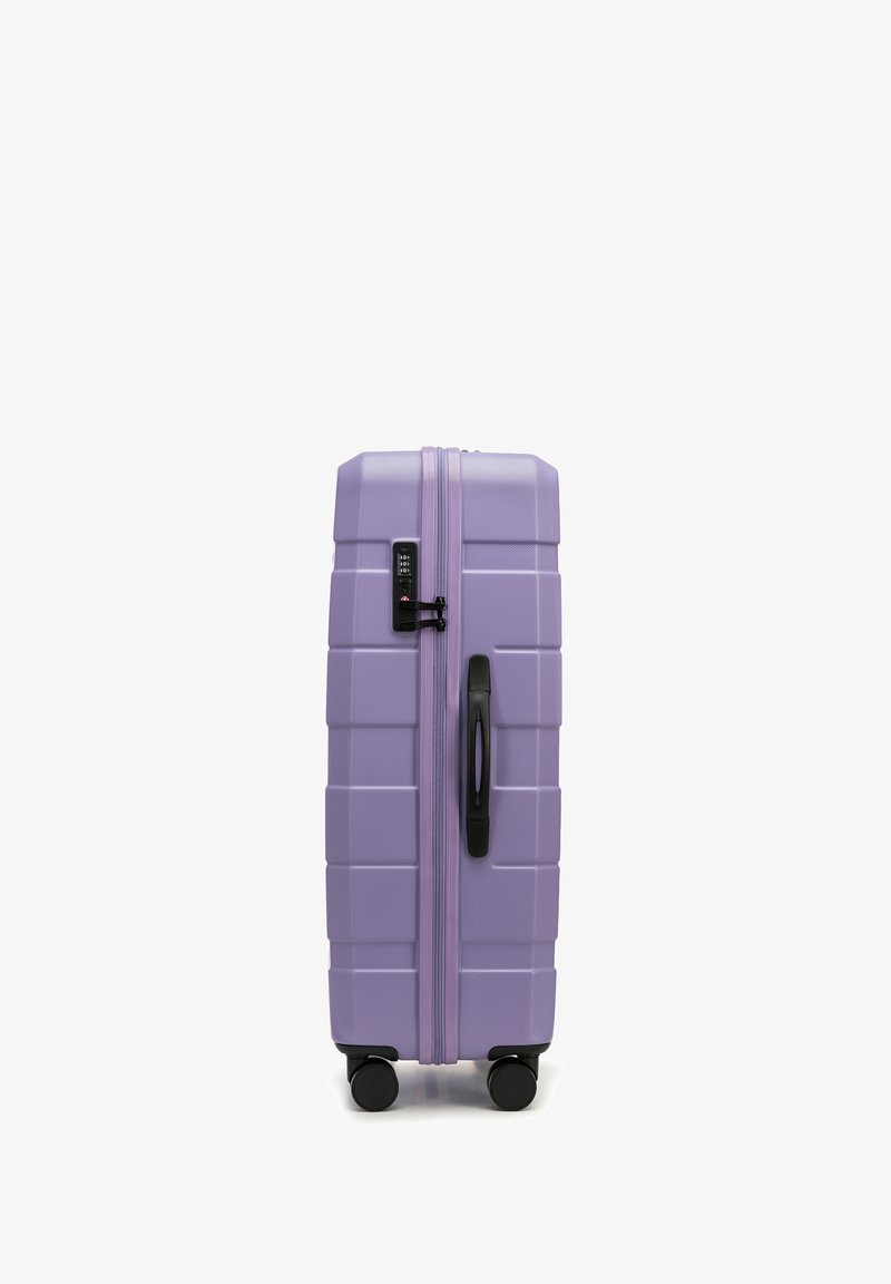 Valise rigide violette avec surface texturée, fermeture éclair noire, serrure à combinaison, poignée supérieure et quatre roues noires pour la mobilité.