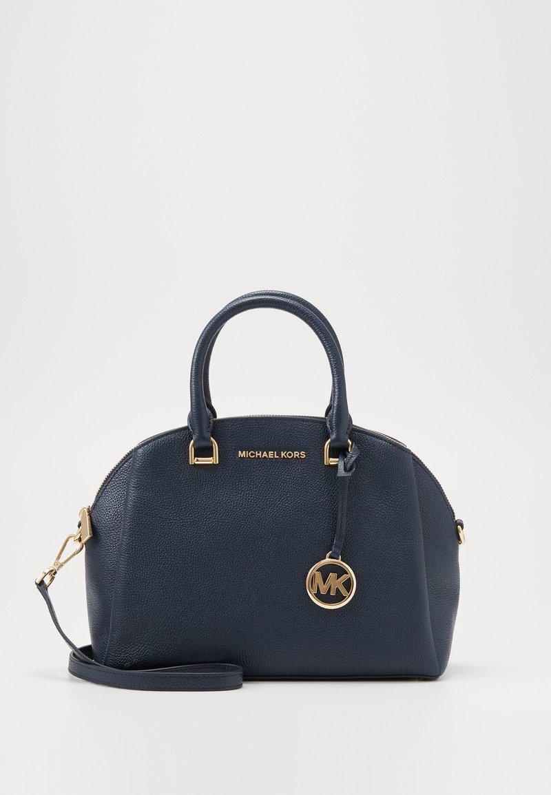 Sac à main en cuir granulé bleu marine avec double poignée, logo Michael Kors doré, breloque ronde MK, et bandoulière amovible.