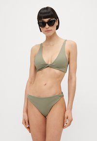 Olíva zöld bikini szett, csavart elülső háromszög felső résszel és alacsony derekú, megkötős alsó résszel, sima textúrával és minimalista dizájnnal.
