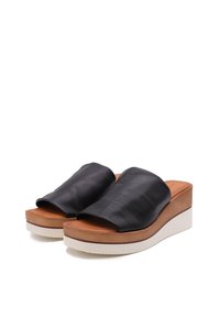 Sandali platform in pelle nera con cinturini larghi, soletta color tan e suola in gomma bianca. Texture liscia con una leggera lucentezza.