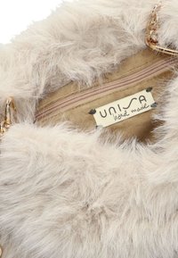 Faux-Fur-Handtasche in hellem Beige mit weicher Textur. Innenraum mit taupefarbenem Futter und einem Reißverschlussfach. Goldene Kettenakzente und ein Etikett mit der Aufschrift "UNISA."