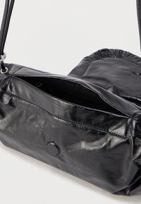 Black faux leather bag with a soft texture, zippered compartment, and drawstring closure, featuring a smooth, rounded shape and minimalist design.