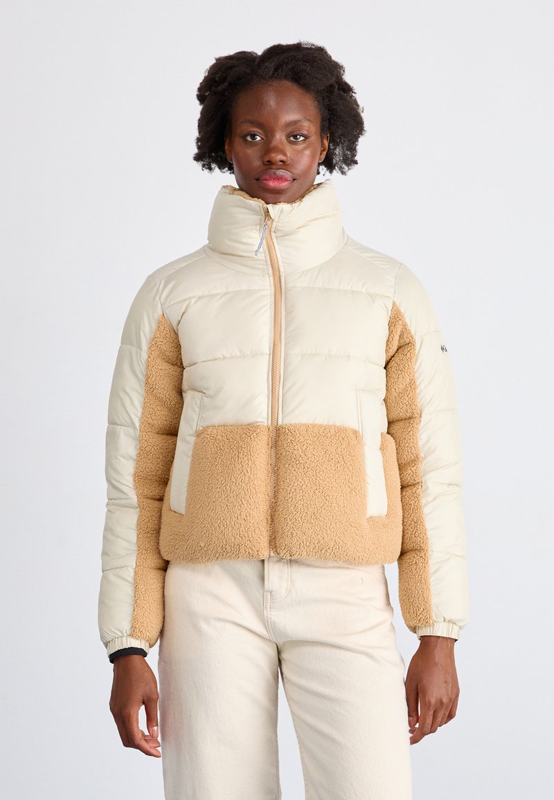 Pufferjacke met een crèmekleurig bovenstuk en een tan fleece onderstuk, hoge kraag, ritssluiting aan de voorkant en elastische manchetten.
