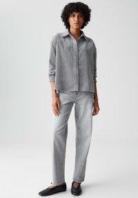 Grijze corduroy overhemd met een kraaglijn, knopen aan de voorkant en lange mouwen, gecombineerd met lichtgrijze rechttoe-rechtaan jeans en zwarte flats.