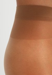 Hautfarbene Shapewear mit elastischem Bund. Glatte Oberfläche aus weichem, elastischem Material, entworfen für einen nahtlosen Look.