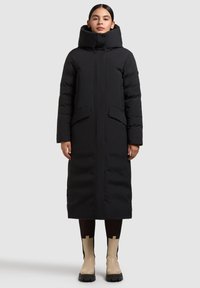 Lang sort dynejakke med høj krave, frontlynlås og to sidelommer; glat stof med en let skinnende finish.