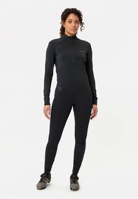 Svart långärmad topp med dragkedja och leggings i en figurnära design, tillverkade av mjukt, stretchigt tyg. Har subtila logotyp- och sömdetaljer.