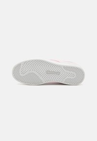 Bijela potplat tenisice s uzorkom chevron i malim heksagonalnim držačima. Logo "Reebok" je vidljiv u elegantnom fontu.