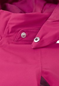 Fuksia värvi kangas, millel on sile tekstuur, sisaldab nupukinnitust ja tugevat kaelust, tuues esile selle funktsionaalsed disainielemendid.