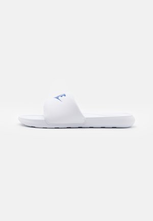 Hvid slidesandal med en tyk rem med blåt Nike-logo, flad sål og struktureret bund for greb.