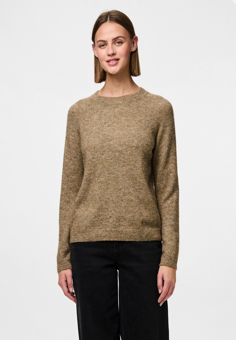 Maglione marrone a trama con scollatura rotonda e maniche lunghe, realizzato in materiale morbido. Indossato con pantaloni neri per un contrasto.