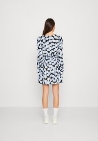 Blommönstrad klänning med långa ärmar, snäv midja och svart bakgrund. Har ljusblå och vita blommor, knälång design.