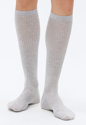 Põlveni ulatuvad sokid heledas hallis, soonilise tekstuuriga. Valmistatud pehmest materjalist, ühtlase värvitooniga, ilma mustrite või aktsentideta.