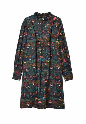 Mujer con vestido oscuro de manga larga hasta la rodilla con estampado colorido de naturaleza y postres, combinado con calcetines blancos arrugados y mocasines marrones.