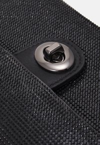 Borsa a pochette nera con superficie testurizzata e piccoli strass neri, chiusura magnetica e bordi in tessuto liscio.