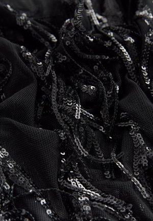 Musta verkkokangas, koristeltu päällekkäisillä mustilla paljeteilla, joissa on teksturoitu, kerroksellinen ulkonäkö ja kiiltäviä yksityiskohtia kauttaaltaan.