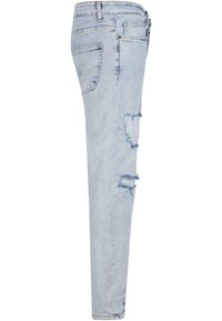 Jean en denim bleu clair délavé avec des trous effilochés sur la cuisse et le genou, avec une poche arrière et des passants de ceinture.