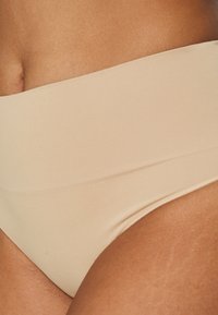 Bikini bottom beige a vita alta, tessuto liscio con texture elasticizzata, caratterizzato da un design senza cuciture e da sottili dettagli di cucitura.