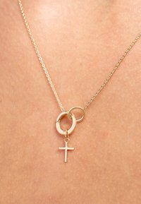 Collier met goudkleurige ketting met in elkaar grijpende ringen en een klein kruisje als hanger. Gladde metaaltextuur, minimalistisch ontwerp en ronde accenten.