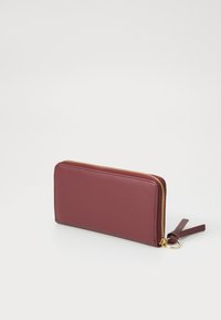 Burgundy wallet with a smooth exterior, gold-toned zipper, and a tassel accent. Features a rectangular shape and slim design.