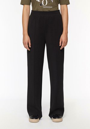 Pantalons larges noirs en tissu doux avec une taille élastique. Présente un design épuré sans motifs ni accents visibles.