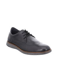 Zapato de vestir negro de piel con acabado suave, detalles de brogue, diseño con cordones y suela de goma gris, con un perfil bajo.