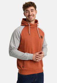 Hoodie met een oranje lichaam en grijze raglanmouwen. Beschikt over een voorkantzak en een logo-opdruk op de borst. Zacht katoenmix materiaal.