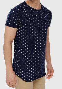 Camiseta de manga corta azul marino con un patrón repetido de diamantes blancos, fabricada en suave algodón con un escote redondeado y dobladillo curvado.