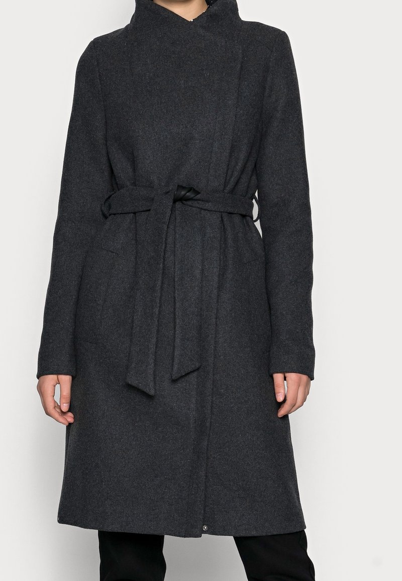 Cappotto lungo in lana grigio scuro con design avvolgente, vita con cintura e due tasche laterali. Presenta un colletto alto e maniche lunghe.